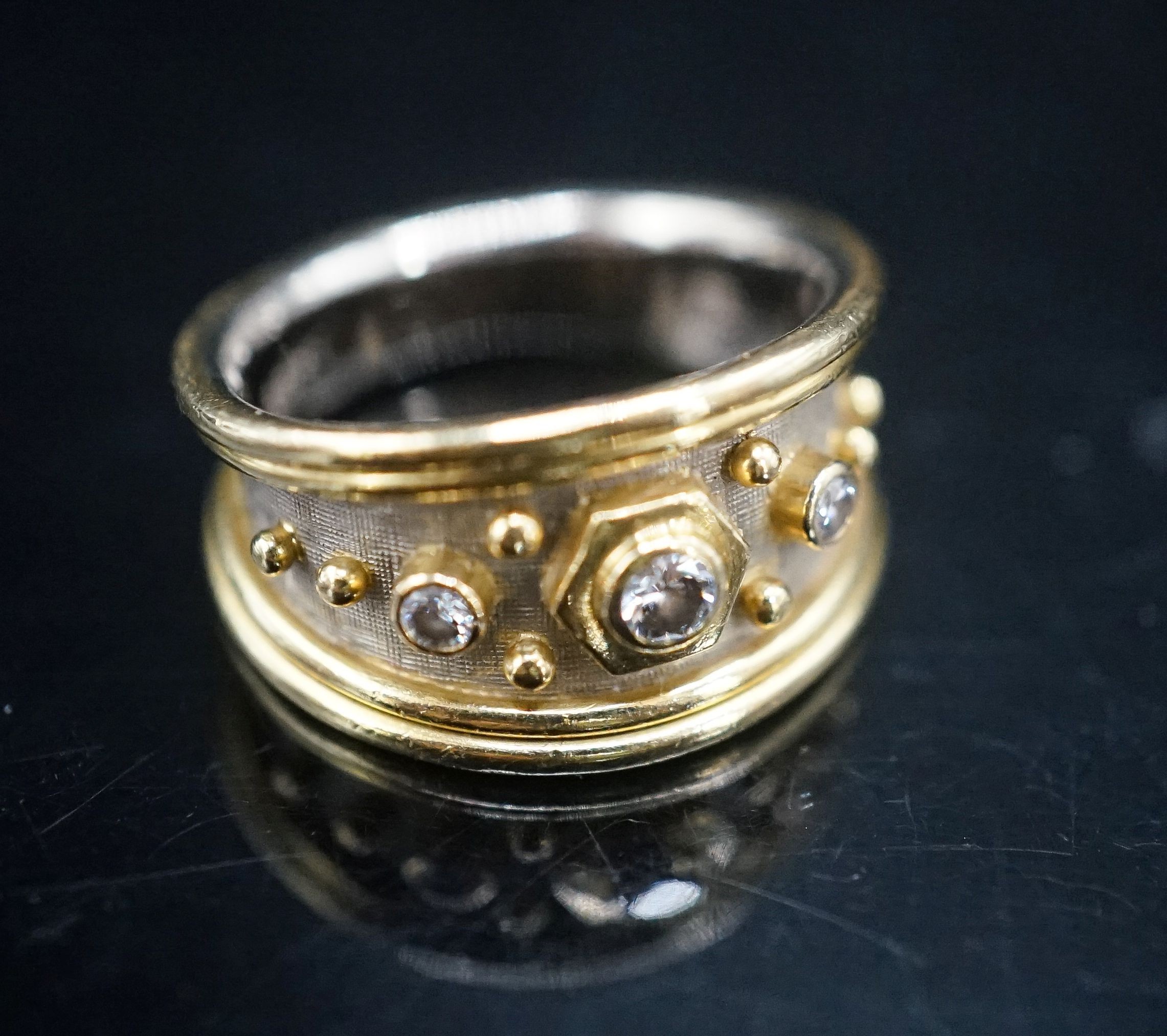 A modern two colour 18ct gold and three stone diamond set dress ring by Elisabeth Gage, size K/L, gross weight 7 grams, with engraved date to shank interior.